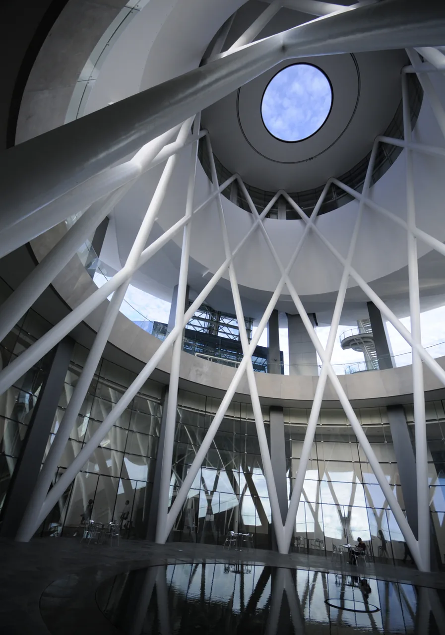 Inside the ArtScience Museum's atrium, white lattice columns rise to a round oculus skylight above a reflecting pool