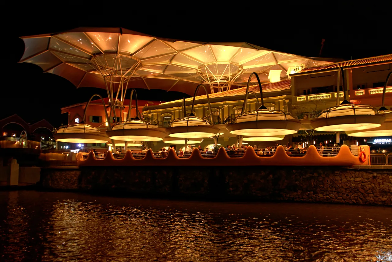 Restored riverside warehouses lit up with bars and restaurants at Clarke Quay on the Singapore River at night