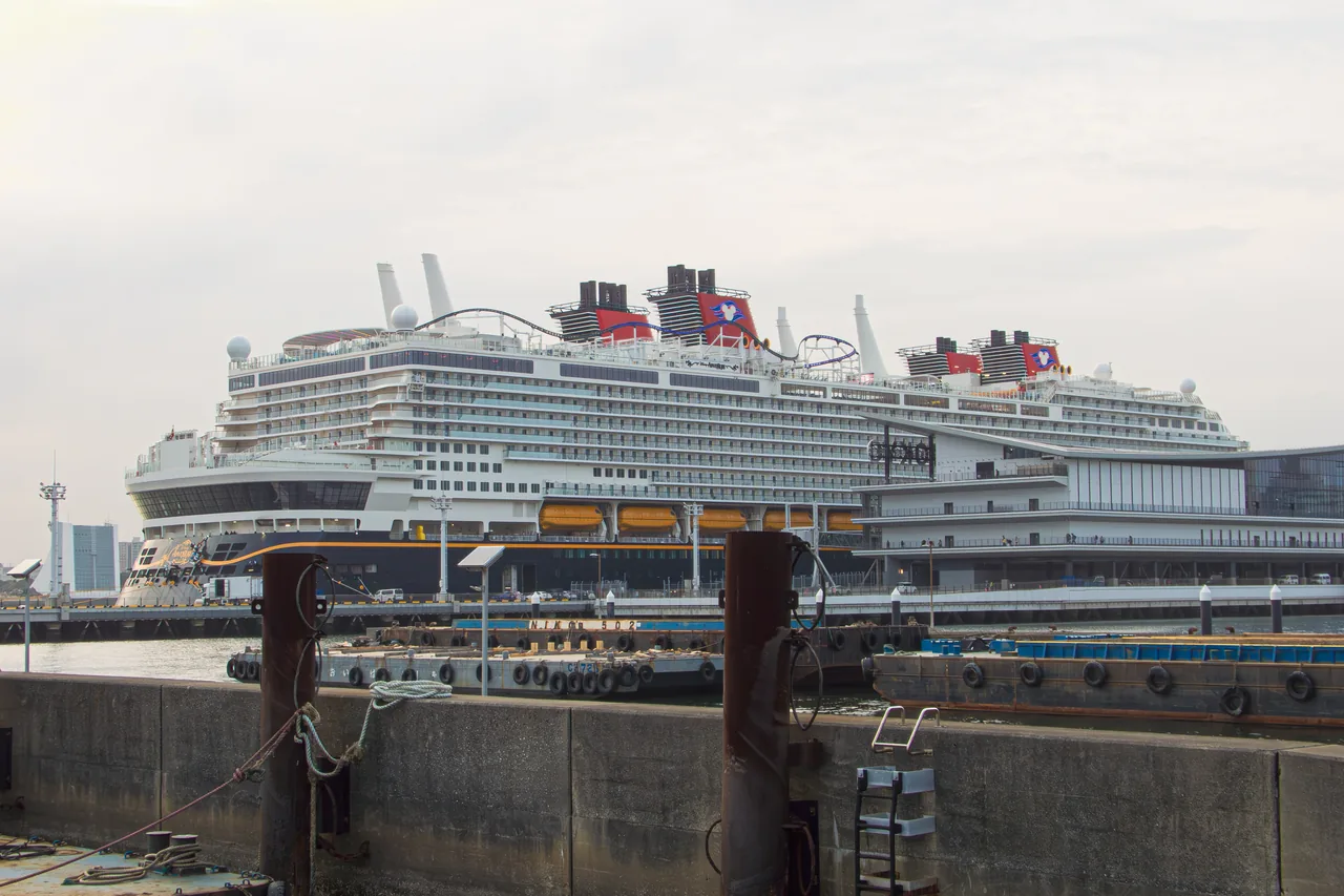 The Disney Adventure cruise ship seen from the side, its top-deck roller coaster visible