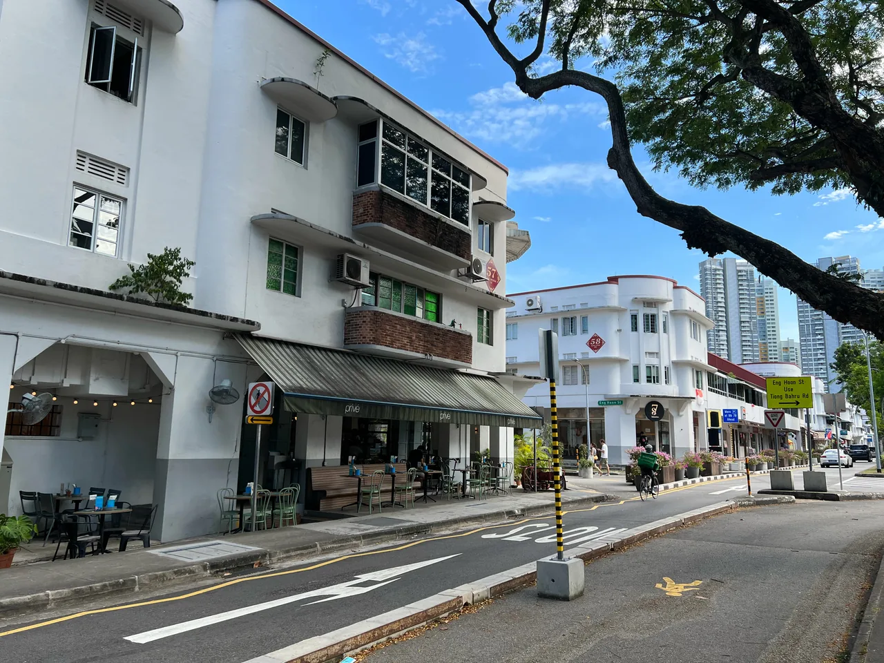 Curving cream-coloured 1930s Art-Deco apartment blocks with a street-level cafe in Tiong Bahru, Singapore