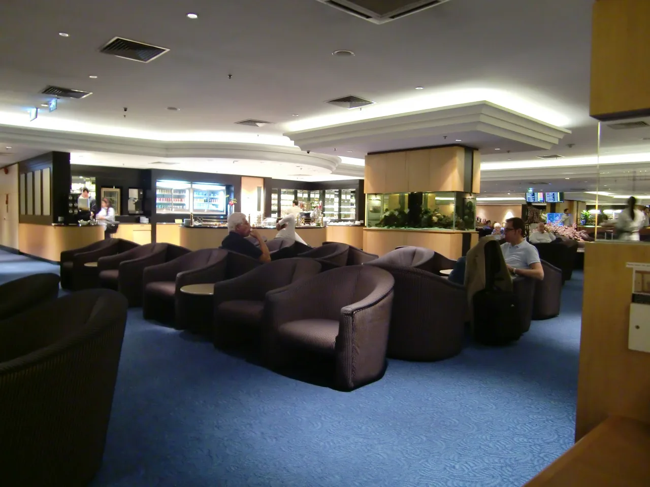 A pay-per-use business lounge at Singapore Changi Airport with lounge seating and a buffet counter A pay-per-use business lounge at Singapore Changi Airport with lounge seating and a buffet counter