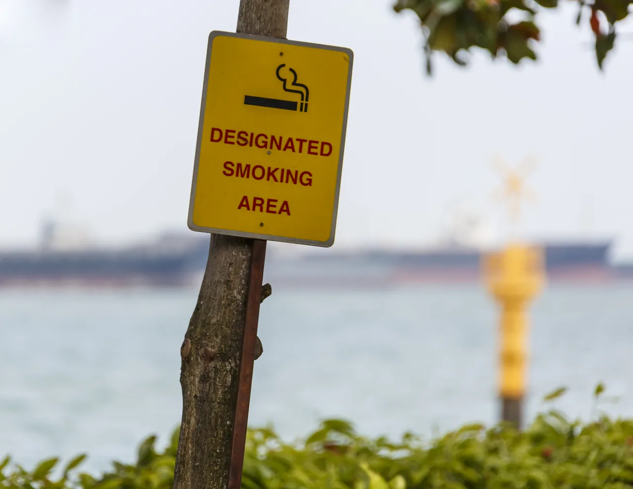 A yellow designated smoking area sign in Singapore