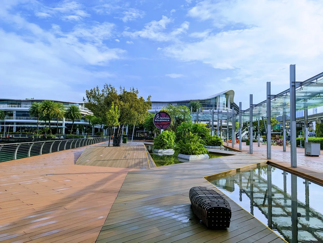 The timber deck and roundel sign at the start of the Sentosa Boardwalk, with the covered walkway to the right