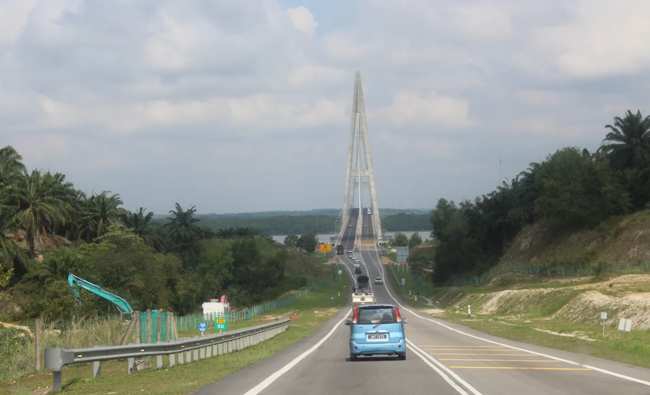 Cars on the Senai to Desaru Expressway approaching the tall pylon of the Sungai Johor cable stayed bridge