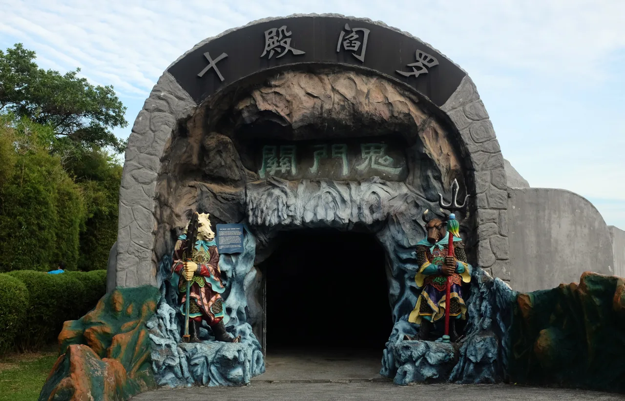 The dragon head entrance to the Ten Courts of Hell at Haw Par Villa, with a guardian figure on each side