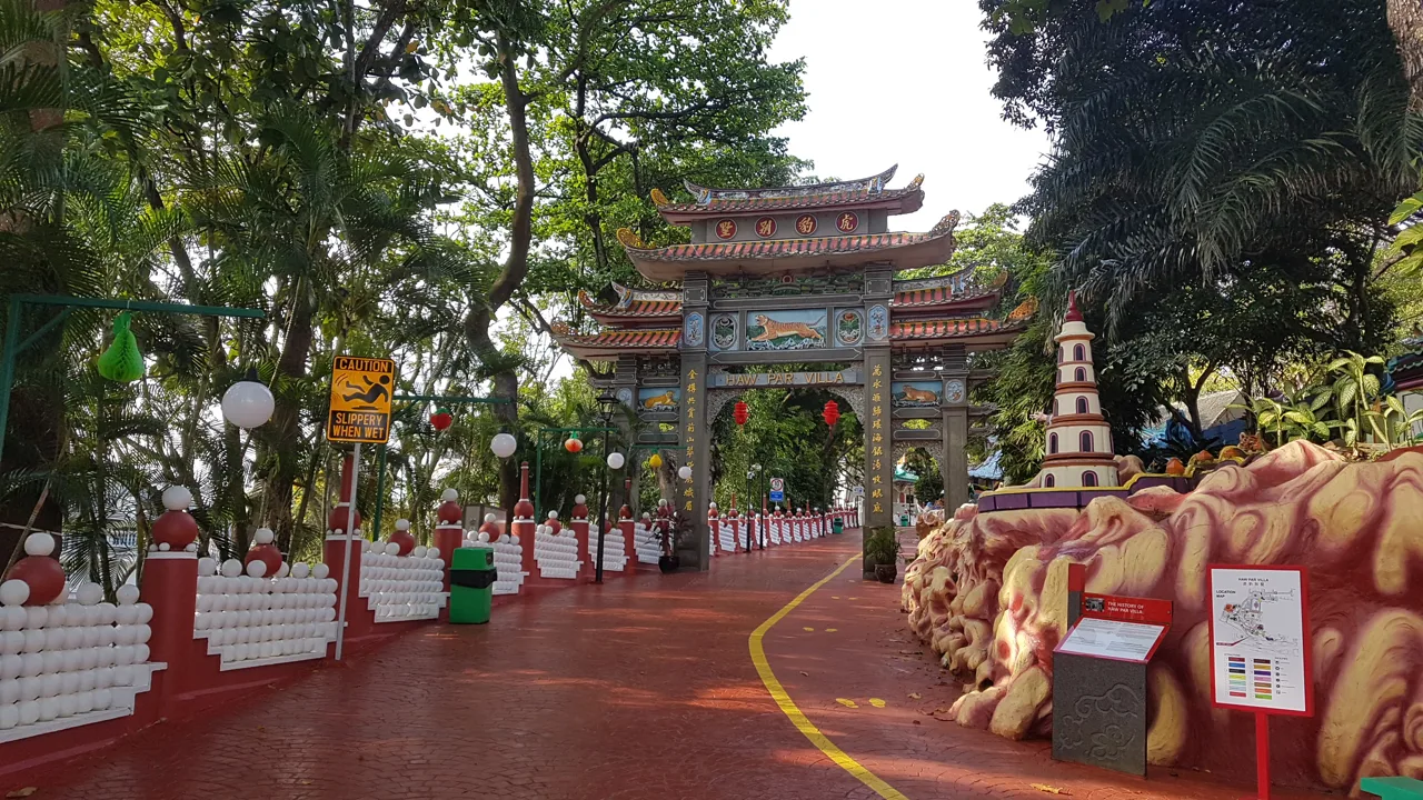 The tiled ceremonial gate at Haw Par Villa seen along a red paved path lined with white balustrades