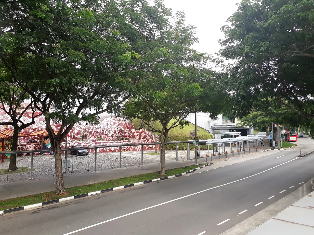Pasir Panjang Road seen from Haw Par Villa station, with the park's white and red rockwork behind the trees