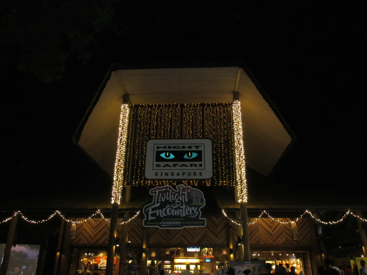 The Night Safari entrance building lit up after dark with visitors walking underneath