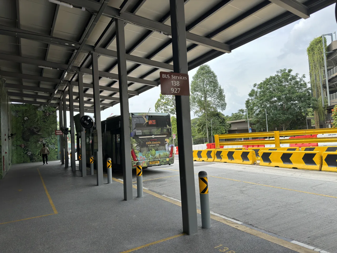A sign reading Bus Services 138 and 927 at the Mandai bus bay, with a Mandai bus waiting behind it