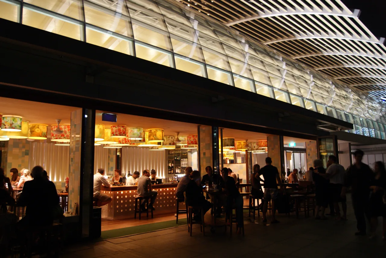 Diners at lit tables outside a restaurant in the Shoppes at Marina Bay Sands in the evening