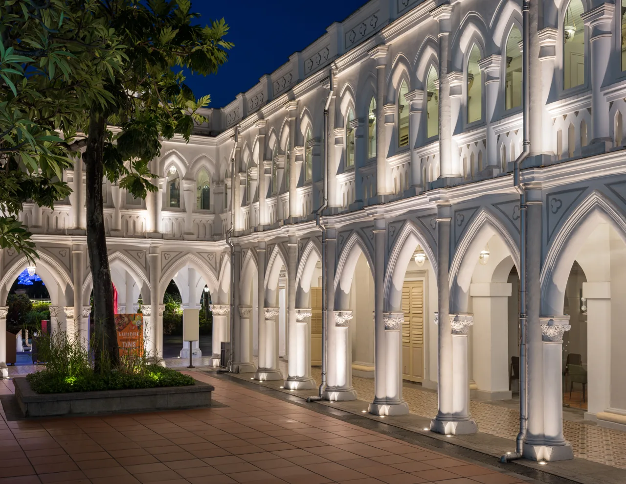 The floodlit gothic arcade of CHIJMES at night with restaurant units under the arches