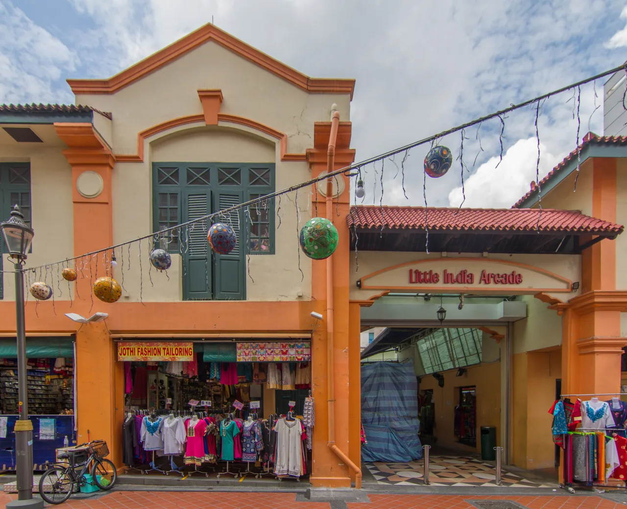 The orange and cream frontage of Little India Arcade on Campbell Lane with clothing displayed outside the shops