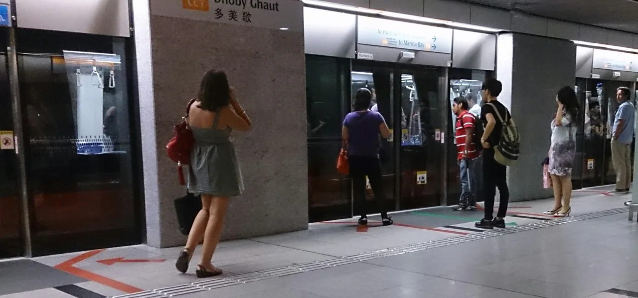 Passengers standing apart on the platform at Dhoby Ghaut MRT station, waiting at the platform screen doors