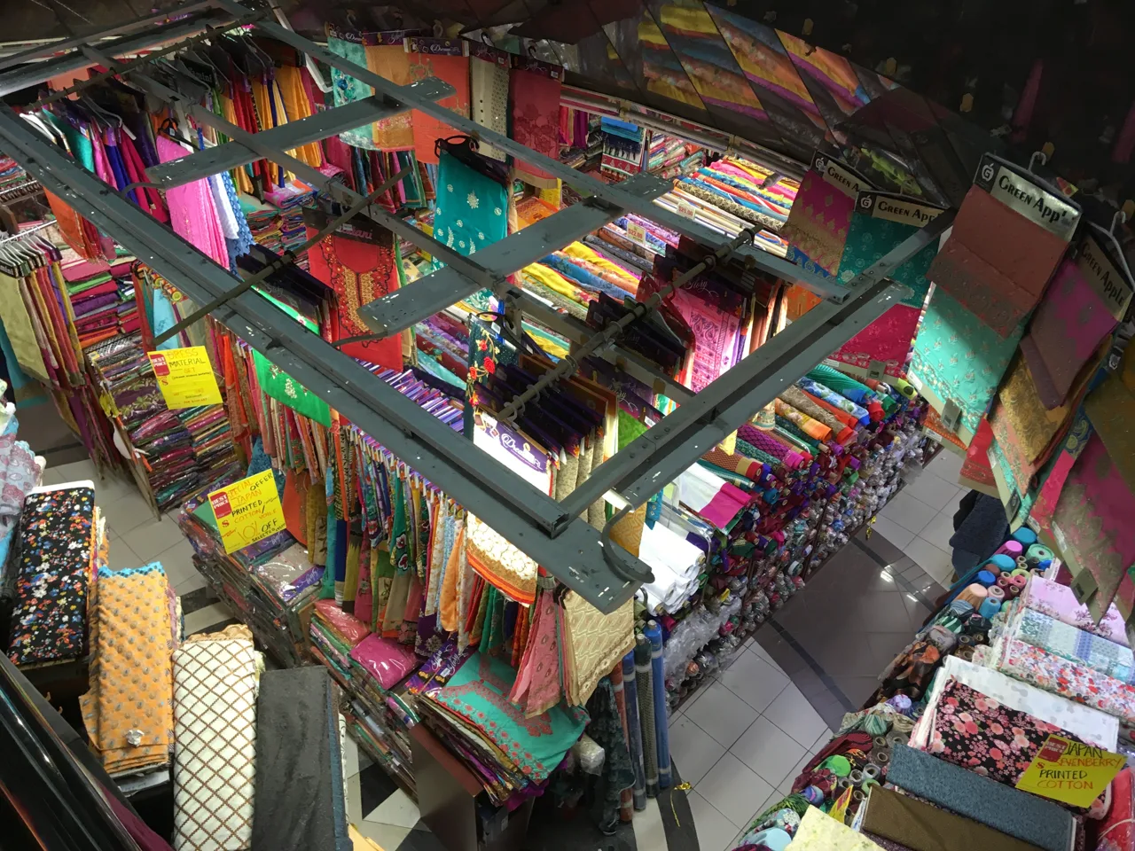 Looking down into a floor of Mustafa Centre stacked with bolts of fabric and hanging garments