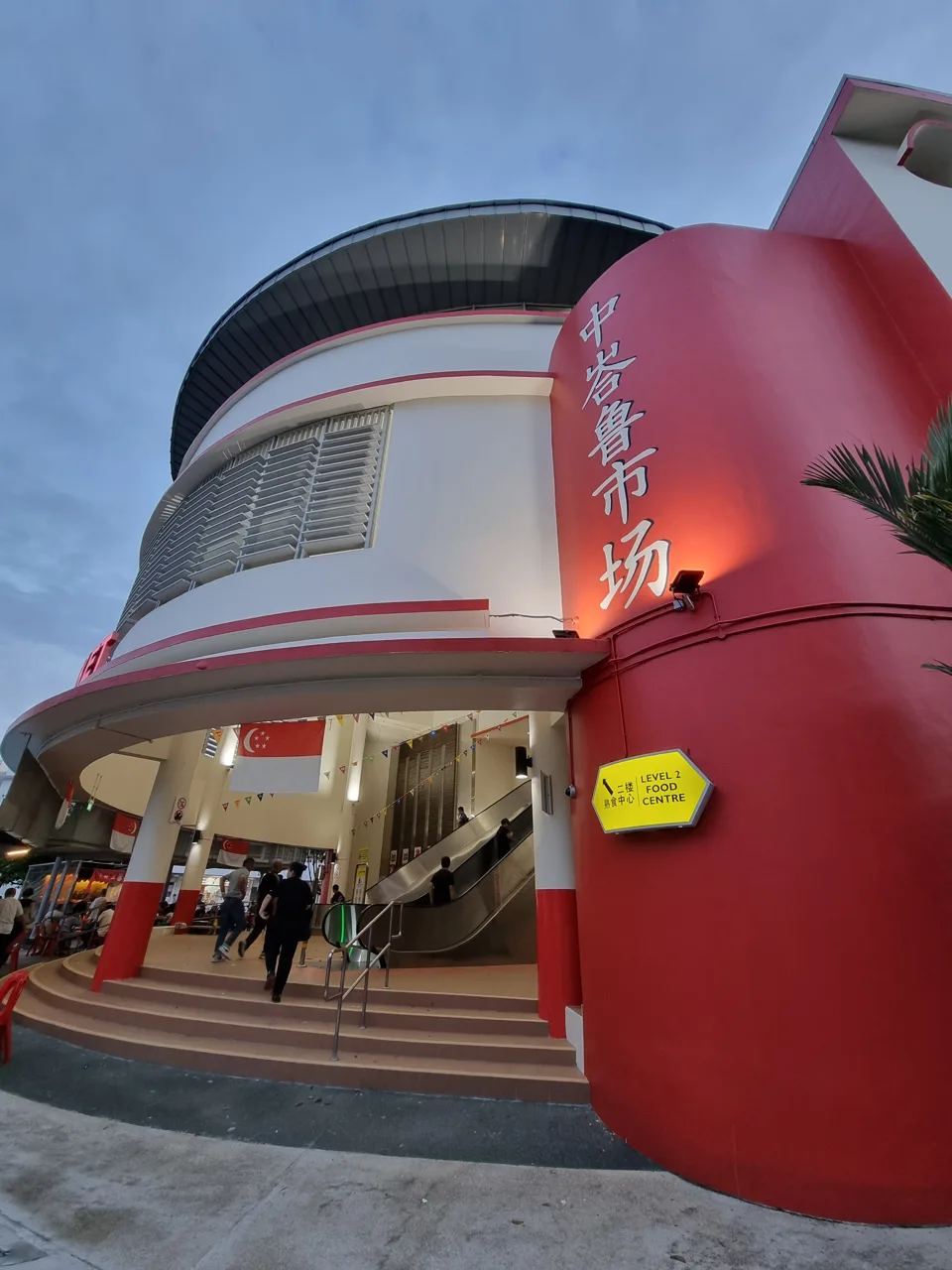 The curved red and white exterior of Tiong Bahru Market with a sign pointing to the Level 2 food centre The curved red and white exterior of Tiong Bahru Market with a sign pointing to the Level 2 food centre