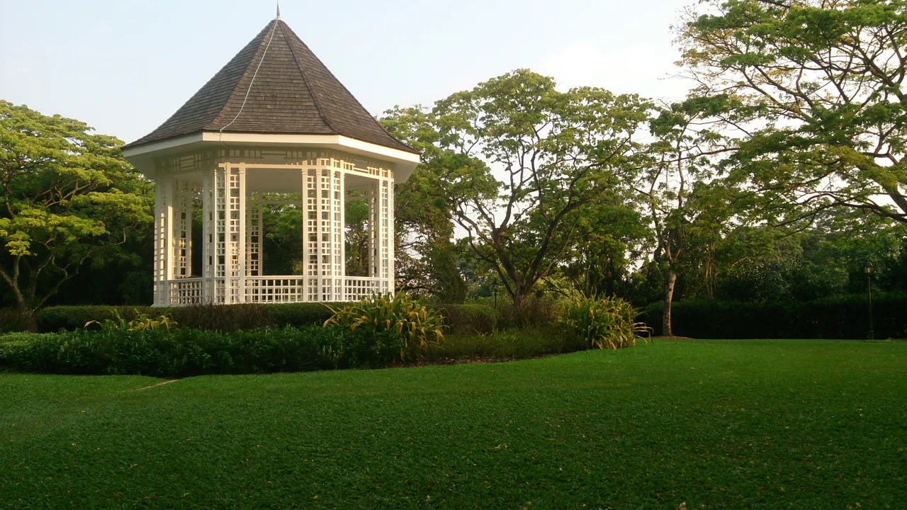 The white bandstand pavilion on a mown lawn ringed by mature trees at Singapore Botanic Gardens The white bandstand pavilion on a mown lawn ringed by mature trees at Singapore Botanic Gardens