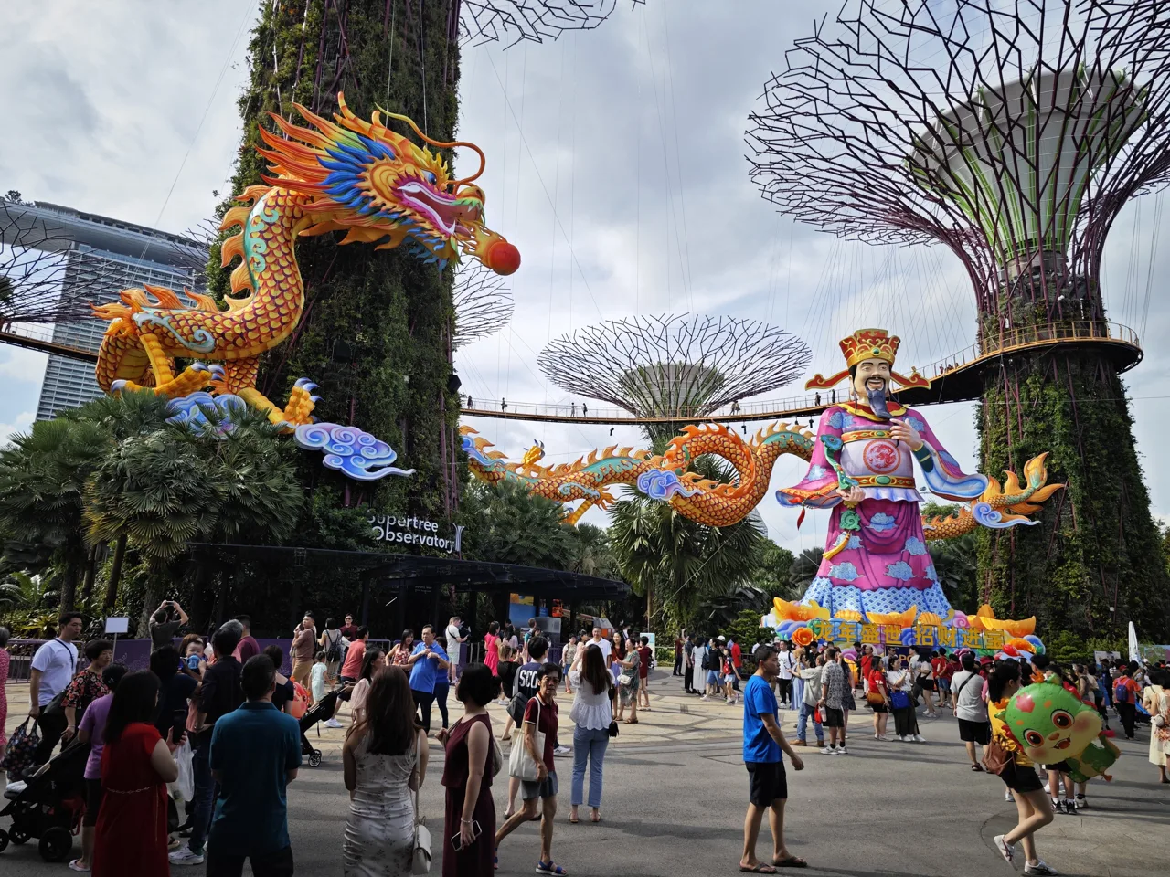 Visitors walking under a long dragon lantern and a tall God of Fortune figure at River Hongbao in Gardens by the Bay