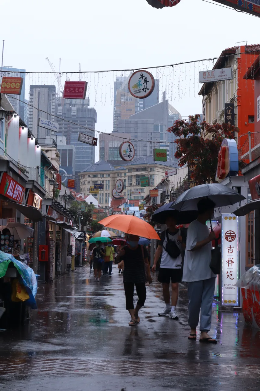 Orang-orang berpayung berjalan di Pagoda Street, Chinatown, saat hujan siang hari