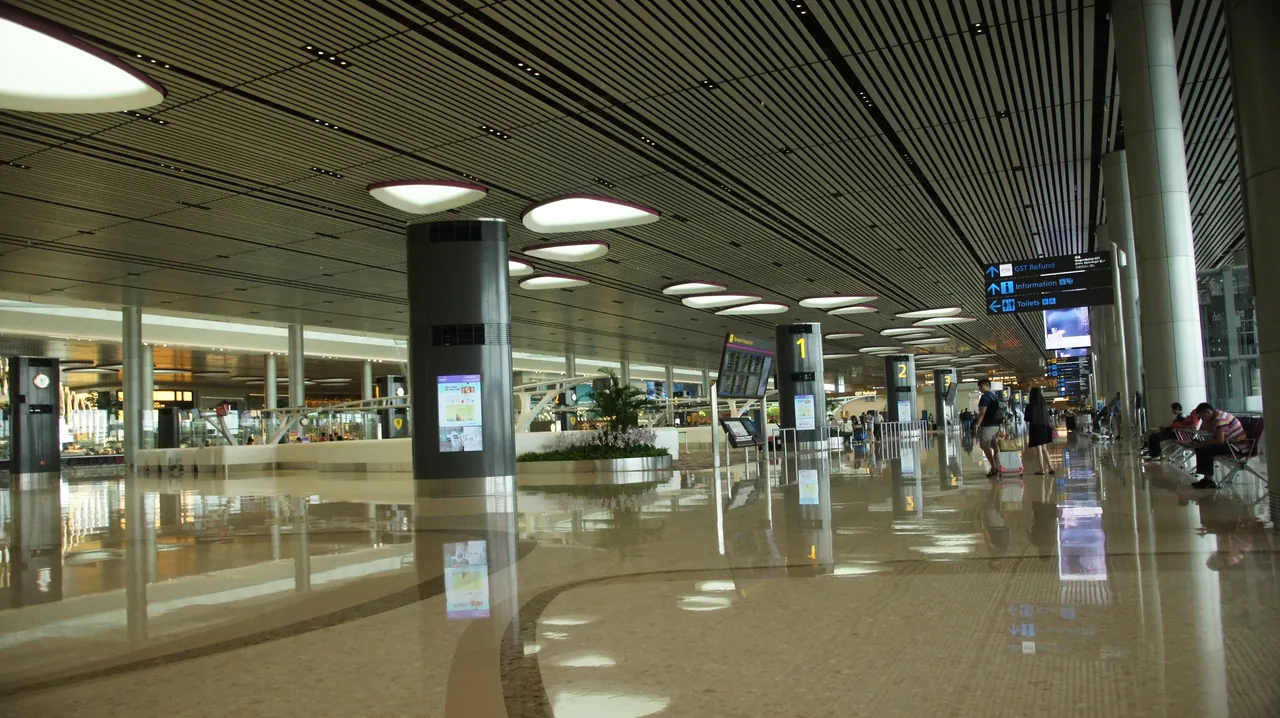 The departure level of Changi Airport Terminal 4, a wide concourse with ceiling lights and check-in areas beyond