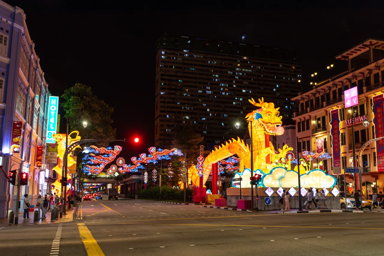A giant golden dragon lantern lit up at night on New Bridge Road in Singapore's Chinatown, with neon dragon arches over the road